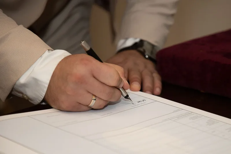 Mão assinando um documento oficial com caneta, como o tradutor público faz ao concluir a tradução juramentada de um histórico escolar