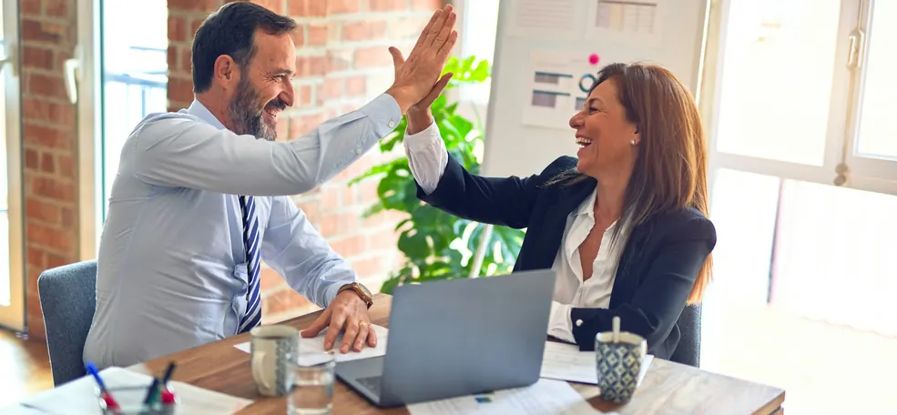 Dois clientes satisfeitos comemorando com um high five após receberem sua tradução juramentada