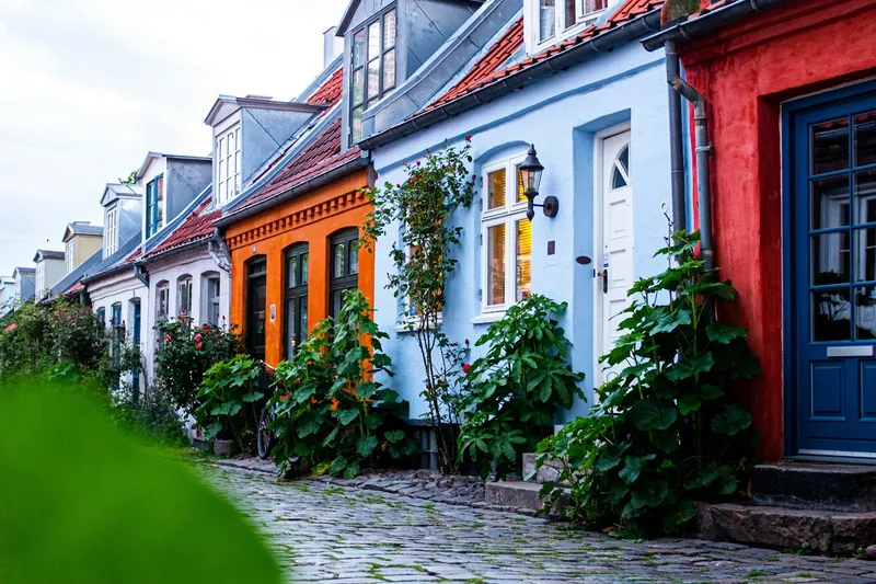 Casas coloridas com portas azul e branca numa rua de paralelepípedos em Aarhus, na Dinamarca