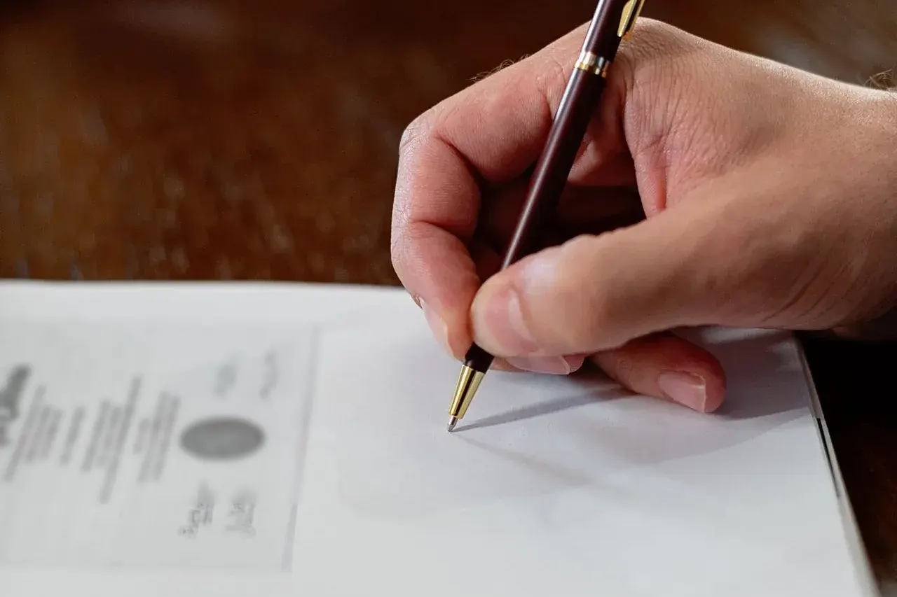Mão com caneta ao lado de um certificado americano com selo oficial, documento em inglês que precisa de tradução juramentada para valer no Brasil